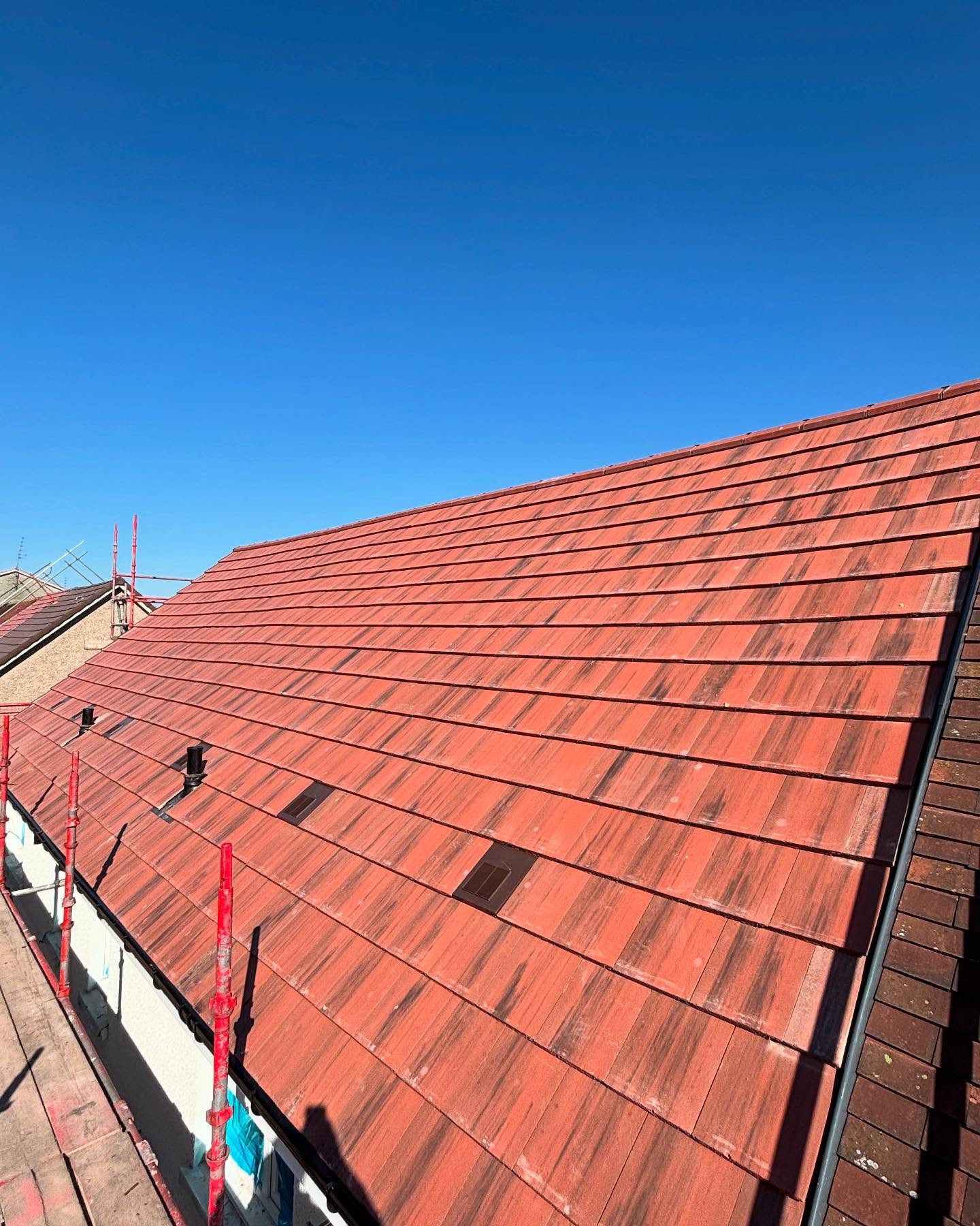 Completed tiled re-roof against a blue sky by LA Roofing