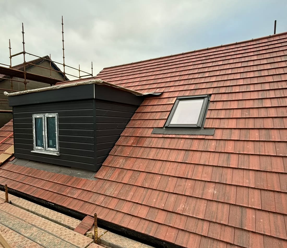Red tiled roof with a clad dormer and roof window by LA Roofing
