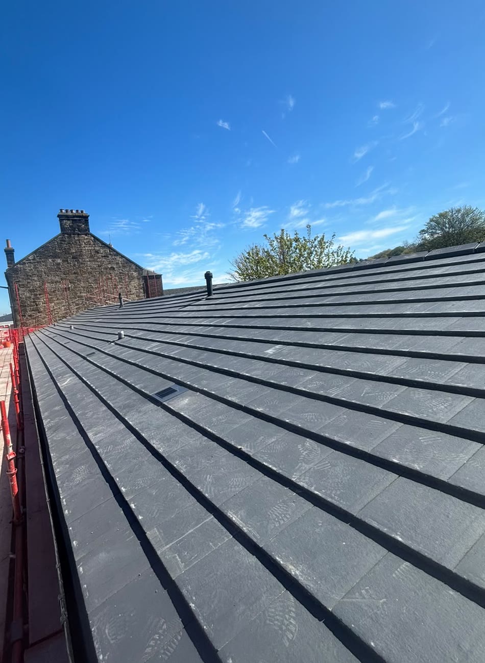 New slate-grey tiled roof under a blue sky