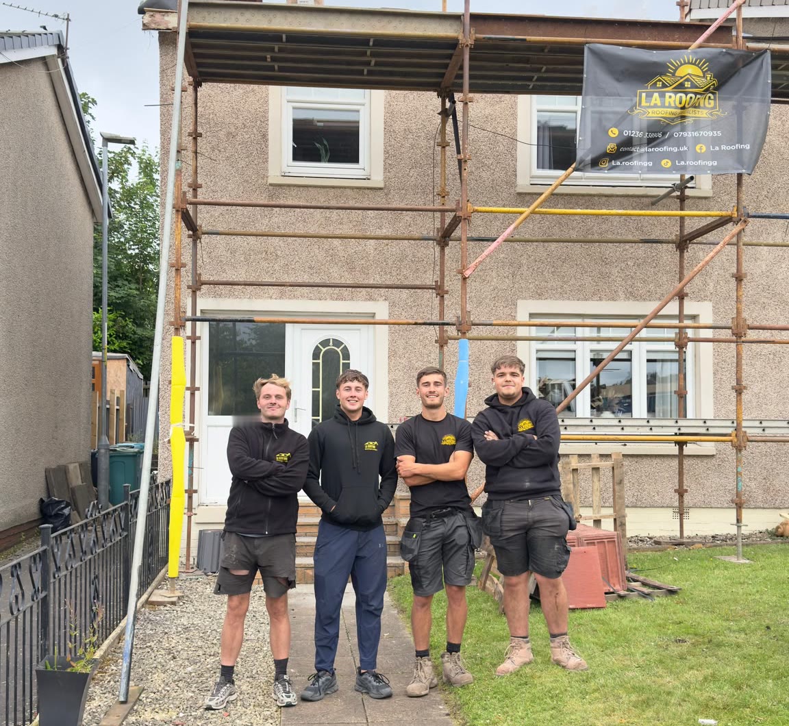 Four of the LA Roofing team in company workwear in front of a scaffolded house with the LA Roofing banner